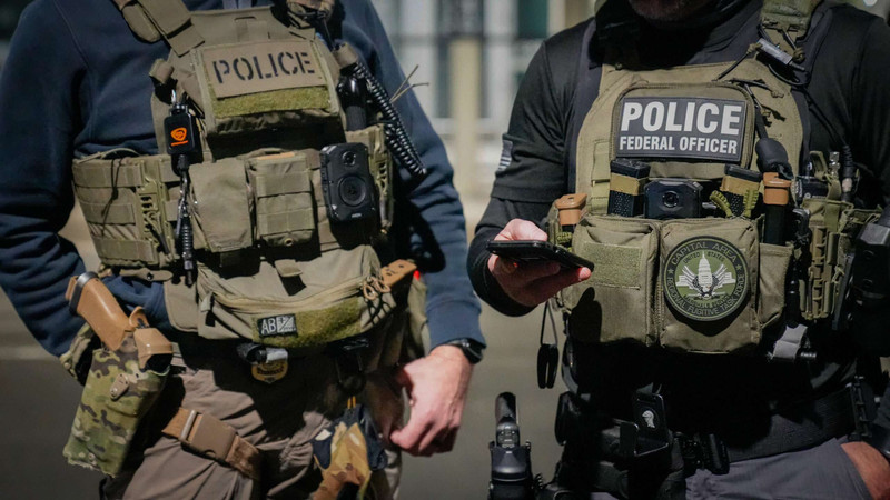 Two-federal-law-enforcement-officers-coordinate-with-other-officials-on-the-ground-during-an-enhanced-immigration-enforcement-operation-near-Washington-D.C.-Feb-scaled.jpg