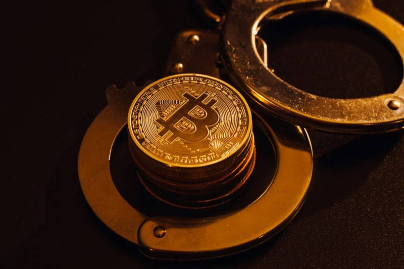 Stack-Of-Bitcoins-And-Handcuffs-Over-Bla.jpeg
